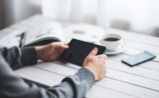 A person is holding an ipad on the table