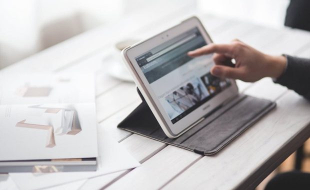 A person using their tablet on the table