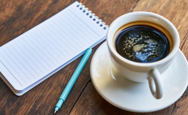 A cup of coffee and a pen on the table